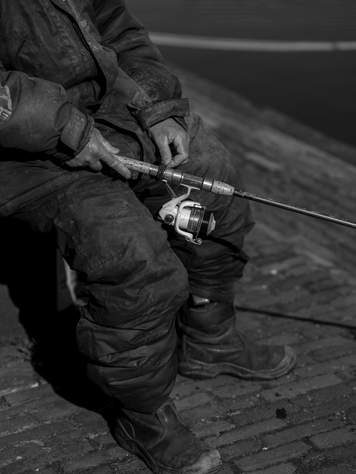 A fisherman prepares his fishing rod for the day.